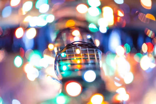 bright multicolored festive lights of a garland around a guitar neck, blurred background