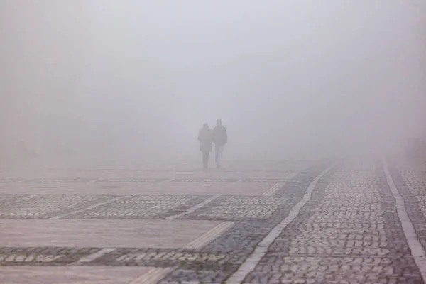 silhouettes of people in a strong dense fog