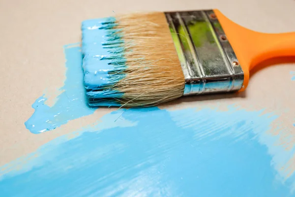 paint brush in blue paint on an unpainted flat surface