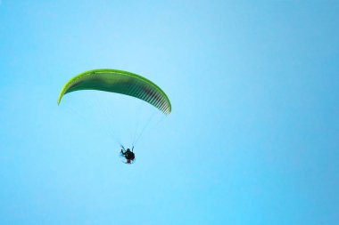 Parlak mavi gökyüzünde uçan yamaç paraşütü