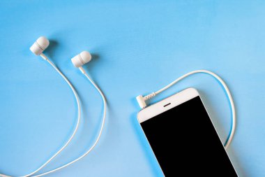 mavi arka planda bağlı beyaz kulaklıklara sahip beyaz akıllı telefon