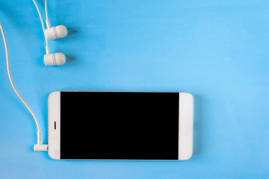 mavi arka planda bağlı beyaz kulaklıklı beyaz akıllı telefon, copyspace