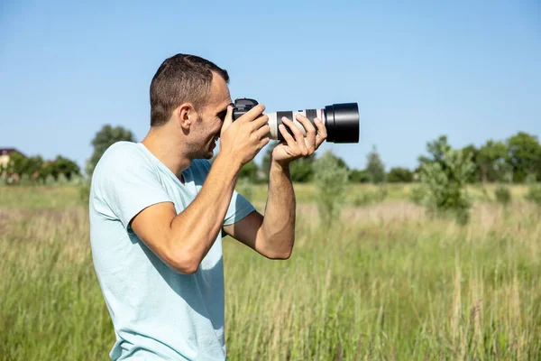 晴れた夏の日に大きなプロ仕様のカメラを持った若い男性写真家が — ストック写真