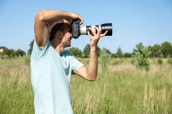 晴れた夏の日に大きなプロ仕様のカメラを持った若い男性写真家が — ストック写真