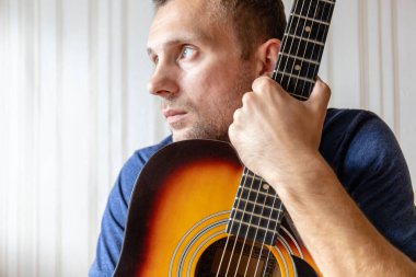Elinde akustik gitarla genç bir adamın yakın çekimi.