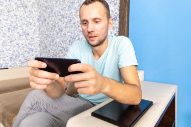 Genç bir adam akıllı telefondan ilginç bir oyun oynuyor.