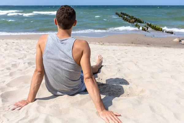 Jovem Bonito Senta Praia Mar Olha Para Distância — Fotografia de Stock