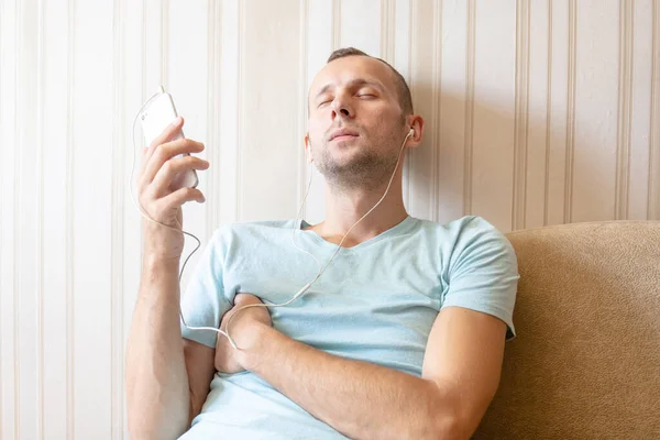 Chico Está Descansando Casa Sofá Escuchando Música Con Auriculares Teléfono —  Fotos de Stock