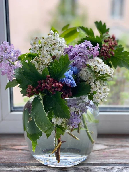 Lilac and other spring flowers in a transparent glass vase,