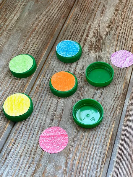 Las tapas de plástico se procesan con papel de color para el juego de los niños . — Foto de Stock