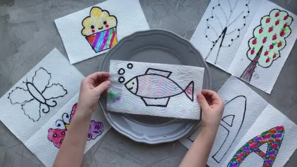 La experiencia mágica de los niños, las manos de los niños ponen el dibujo en un plato de agua, los peces se vuelven coloridos, los niños artesanos . — Vídeos de Stock