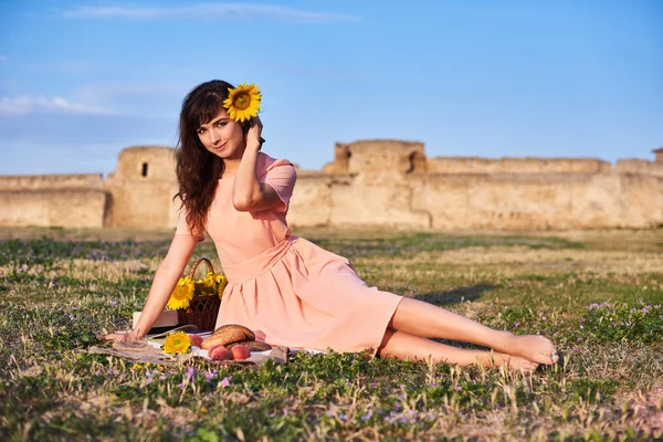 一个美丽的女人坐在草地上 有城墙的背景 — 图库照片
