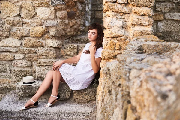 坐在旧城堡台阶上的女孩拿着她的头发 — 图库照片