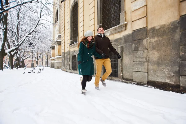 Happy couple playful together during winter holidays vacation outside in snow old center