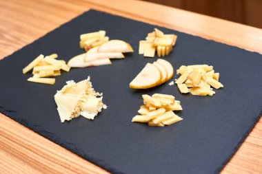 ahşap masa üzerinde taş tahta üzerinde farklı peynir ile plaka