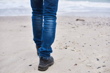 Kot pantolon ve yol boyunca yürüyüş siyah spor ayakkabı giyen yalnız kadın