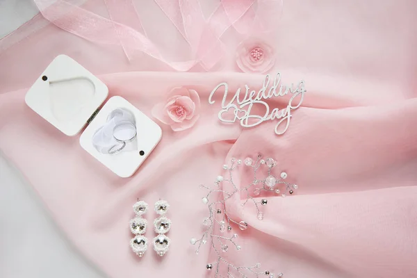 Flores de tecido decorativo, jóias nupciais em chiffon rosa sobre fundo de papel branco - vista superior — Fotografia de Stock