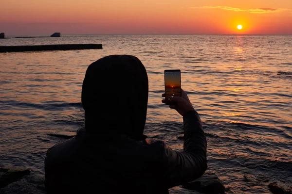 男人用手机拍摄日落的照片。旅行青年正在用手机相机拍摄美丽的日出风景的视频和照片。暑假旅游和度假 — 图库照片