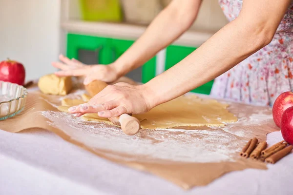 Woman kneading dough for the apple pie on kitchen table. Rustic style