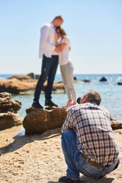 Fotógrafo y pareja en el amor, playa sesión de fotos en el día soleado, hombre tomando fotos de mujer joven y hombre — Foto de Stock