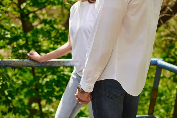 Piernas de joven abrazando pareja en escaleras en verde parque — Foto de Stock