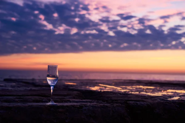 A glass of white wine at the seaside sunrise background