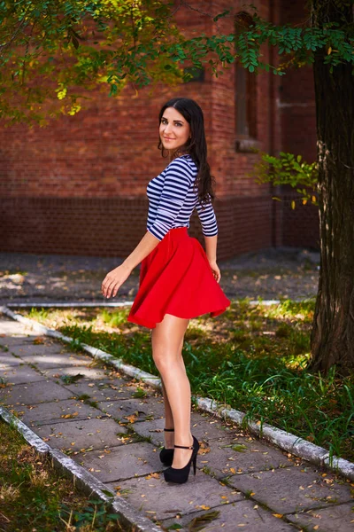 Ung kvinna snurrar i parken. flicka i röd kjol dans utomhus — Stockfoto