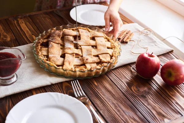 Woman cutting a dessert of freshly baked apple pie on wooden the table — Stock Photo, Image