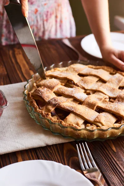 Woman putting delicious american pie on table. Close-up woman's hands cutting a homemade apple pie. White plates on the table — Stock Photo, Image