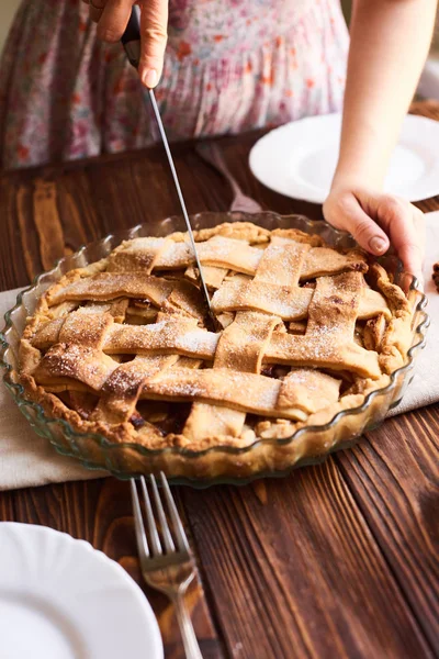 Kvinde lægger lækker amerikansk tærte på bordet. Close-up kvindes hænder skære en hjemmelavet æbletærte. Hvide plader på bordet - Stock-foto