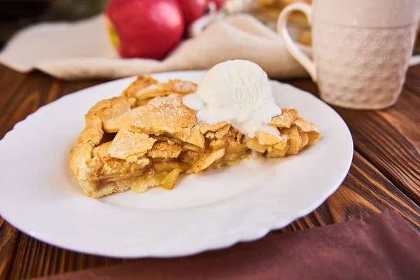 Tasty homemade apple pie, slice with ice cream. Apples. Plate, linen towel Wooden background Cup of tea — Stock Photo, Image