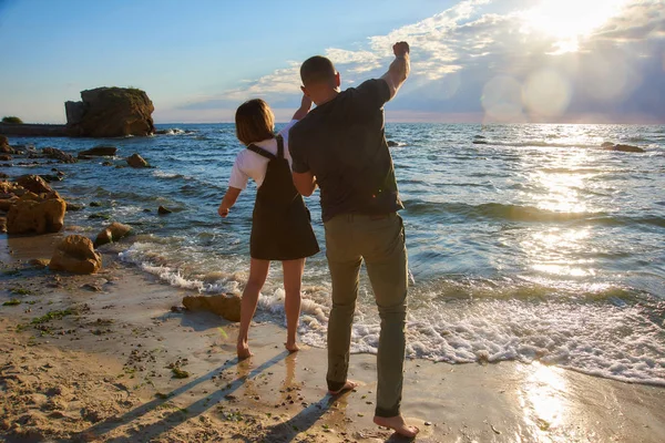 Coppia affettuosa all'alba spiaggia gettando una pietra in mare. bello romantico amore sfondo — Foto Stock