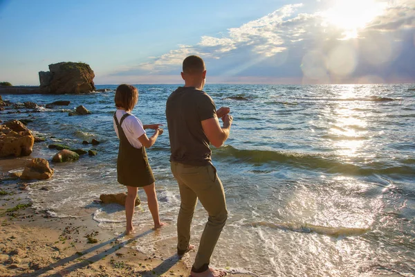 Feliz pareja amorosa conocer el amanecer y jugar en la playa en la orilla del mar. resplandor del sol en el marco —  Fotos de Stock