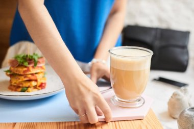 Sabah kahvesi. Bir kafede kahve fincanı ile kadınların ellerini yakın çekim. Bir kafede ahşap bir masa arka plan üzerinde latte fincan tutan kadın elleri, vintage renk tonu