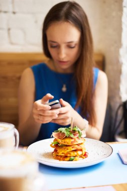 Cep telefonuyla kafede leziz gözleme yiyen güzel genç bir kadın.
