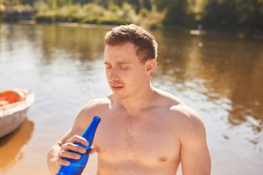 Sabah egzersiz ve içecekler su sonra nehir veya göl kenarında duran çıplak gövde ile Güçlü vücut geliştirmeci