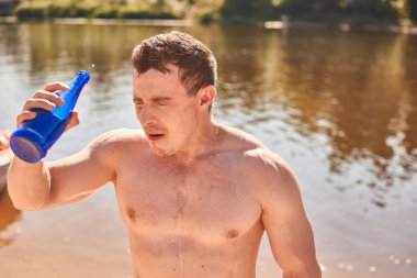 Sabah egzersiz ve içecekler su sonra nehir veya göl kenarında duran çıplak gövde ile Güçlü vücut geliştirmeci