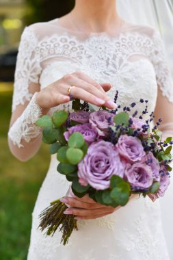 Ellere odaklan. Leylak mor tonlarında düğün buketi yakın çekim. Güller ve lavanta