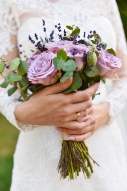 Ellere odaklan. Leylak mor tonlarında düğün buketi yakın çekim. Güller ve lavanta