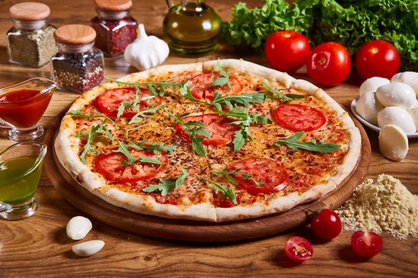 Tahta masada servis edilen lezzetli İtalyan pizzası. Domates soslu pizza margarita, taze mozzarella, parmesan ve ahşap arka planda fesleğen.