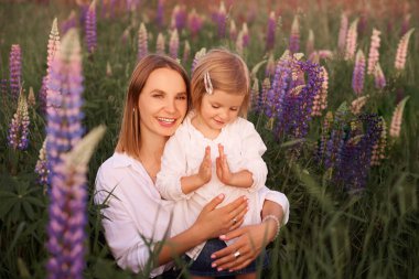 Doğada mutlu aile günleri. Anne ve kızı çayır tarlalarında birlikte oynuyorlar.