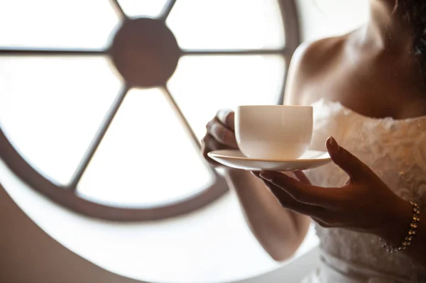 Bräute reichen sich die Hände mit einer Tasse Kaffee. Braut am Fenster — Stockfoto