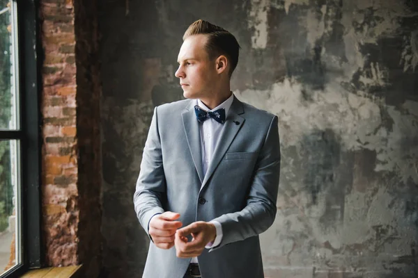 Morning of the groom. Groom morning preparation. Young and handsome groom getting dressed in a wedding shirt