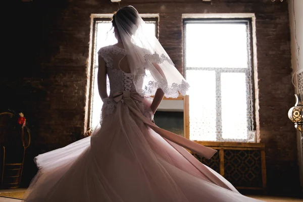 Die Braut versammelt sich am Morgen vor dem Spiegel. die Braut versammelt sich am Morgen. stilvolles rosa Hochzeitskleid. die Braut dreht sich in einem Kleid neben dem Spiegel. — Stockfoto