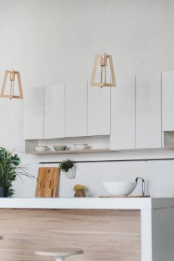 Beyaz ve kahverengi ahşap şık mutfak. Stil minimalizmi. Lavabo, masa üstü, bitkiler, saksı, yemekler için raf.
