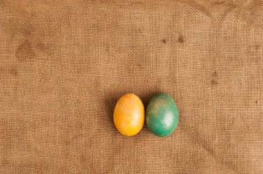 Sarı ve mavi parlak yumurtalar çuval bezinin üzerinde duruyor. Paskalya yumurtası. Mutlu Paskalyalar. Kopyalama. Paskalya yumurtalı arka plan. Metin için yer