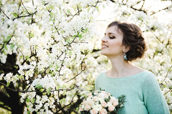 Retrato de una joven en el jardín florecido en primavera. Mujer hermosa joven en el jardín floreciente . — Foto de Stock