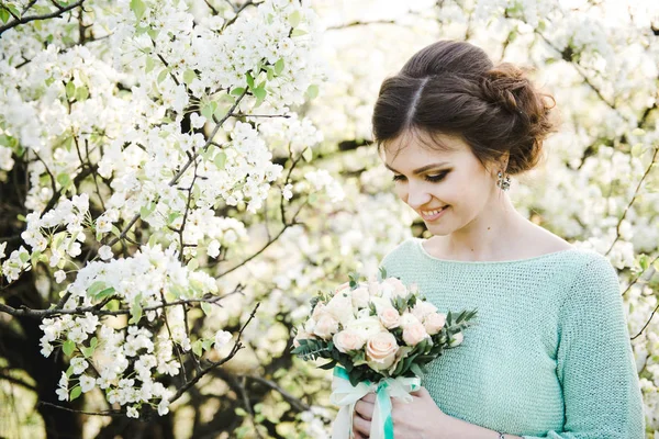 Retrato de una joven en el jardín florecido en primavera. Mujer hermosa joven en el jardín floreciente . — Foto de Stock