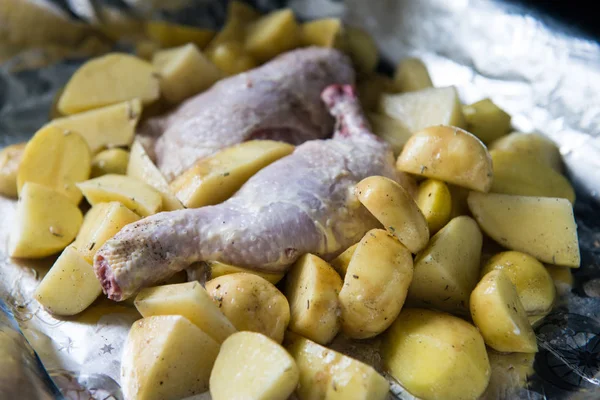 Raw chicken leg with potatoes ready to be cooked. Raw chicken with raw potatoes in the form for baking, ready to be cooked.