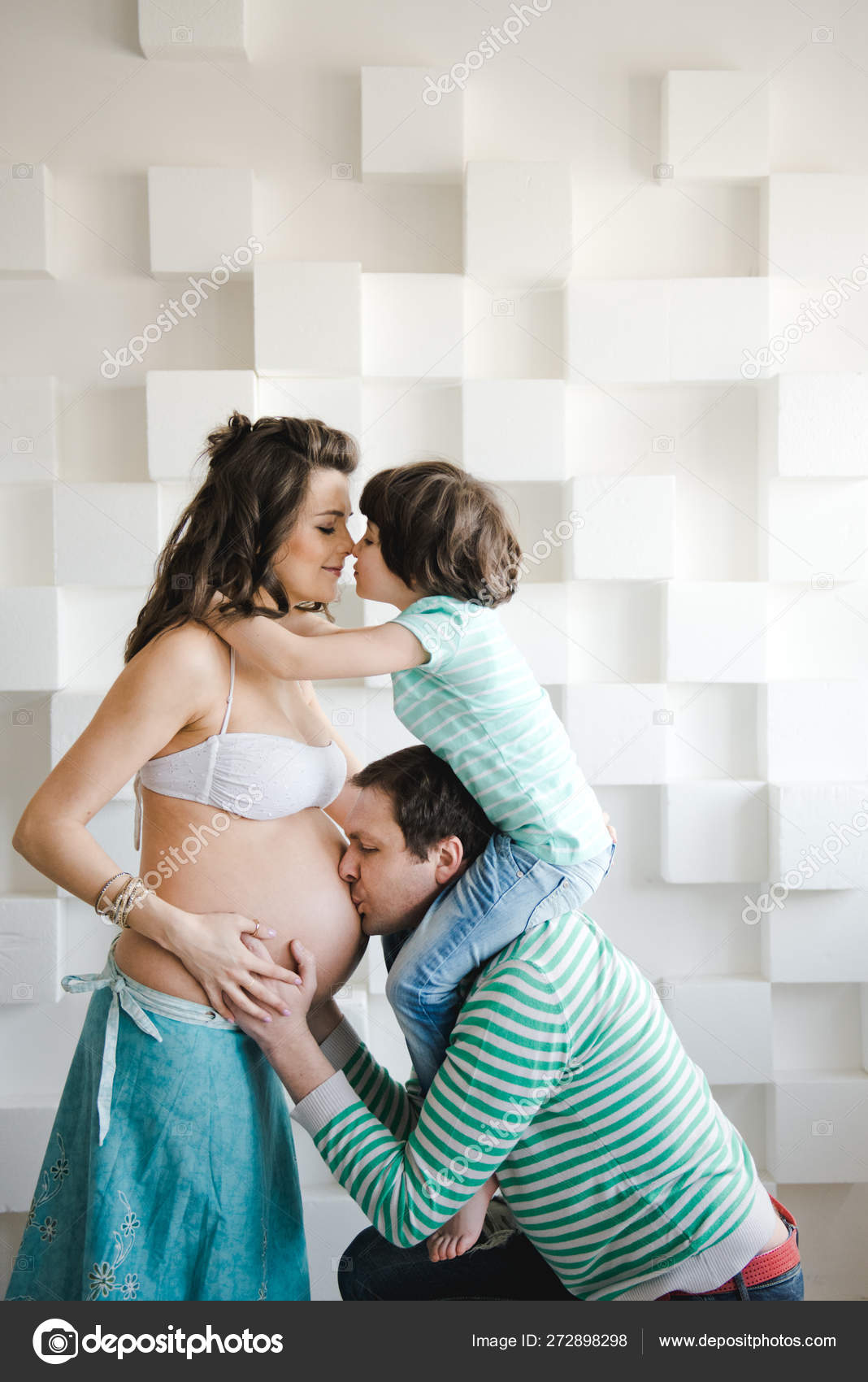 Man is kissing his pregnant wifes belly. Last months of pregnancy. Pregnant woman with husband and little boy . Happy family waiting for a second child